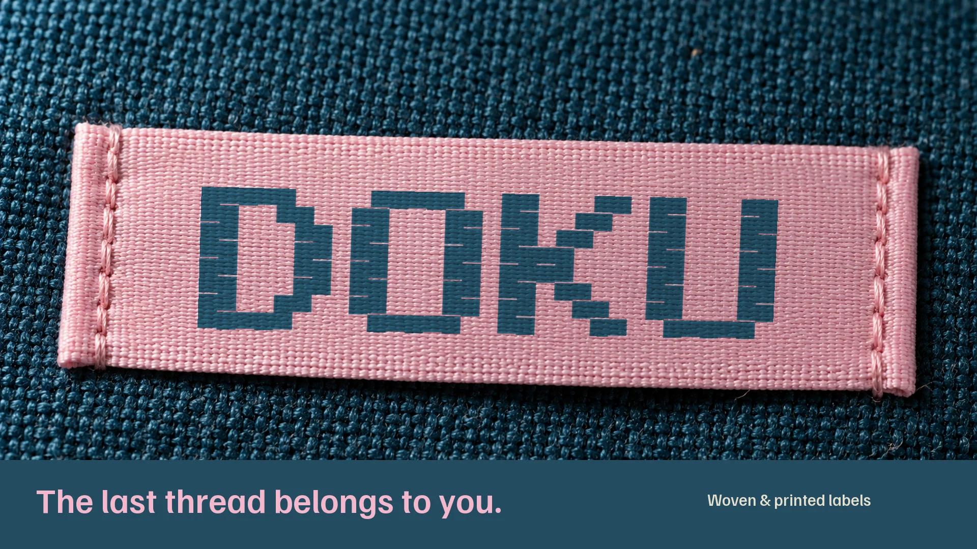 Doku woven wordmark on a pink label with visible thread texture